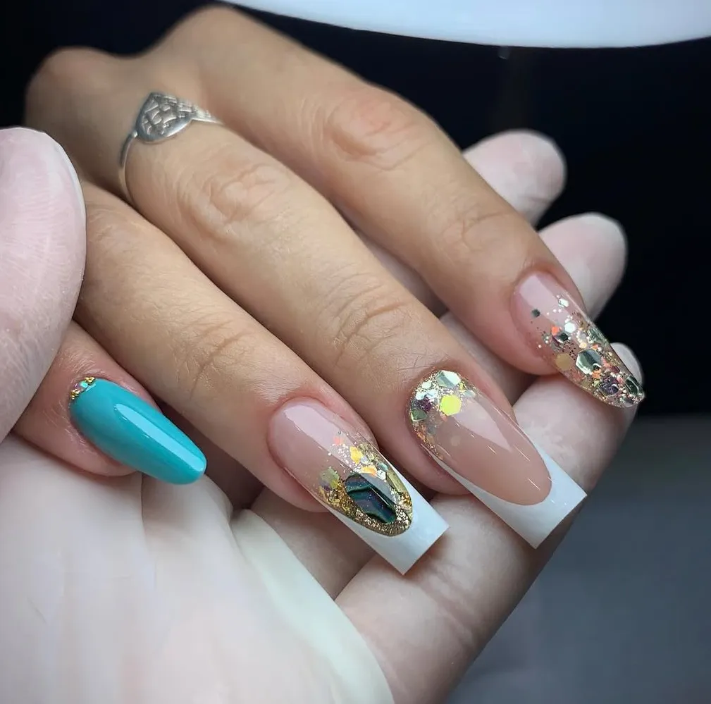 Uñas francesas largas con foil dorado, glitter y una uña turquesa